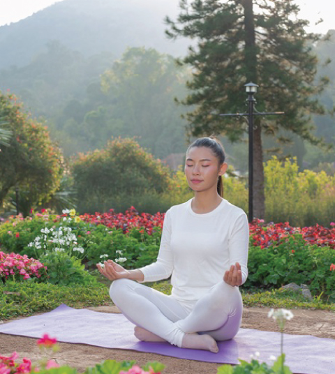 Guest practicing yoga and meditation at Ojaswi Resort in Mukteshwar, surrounded by lush gardens and Himalayan nature for wellness and relaxation